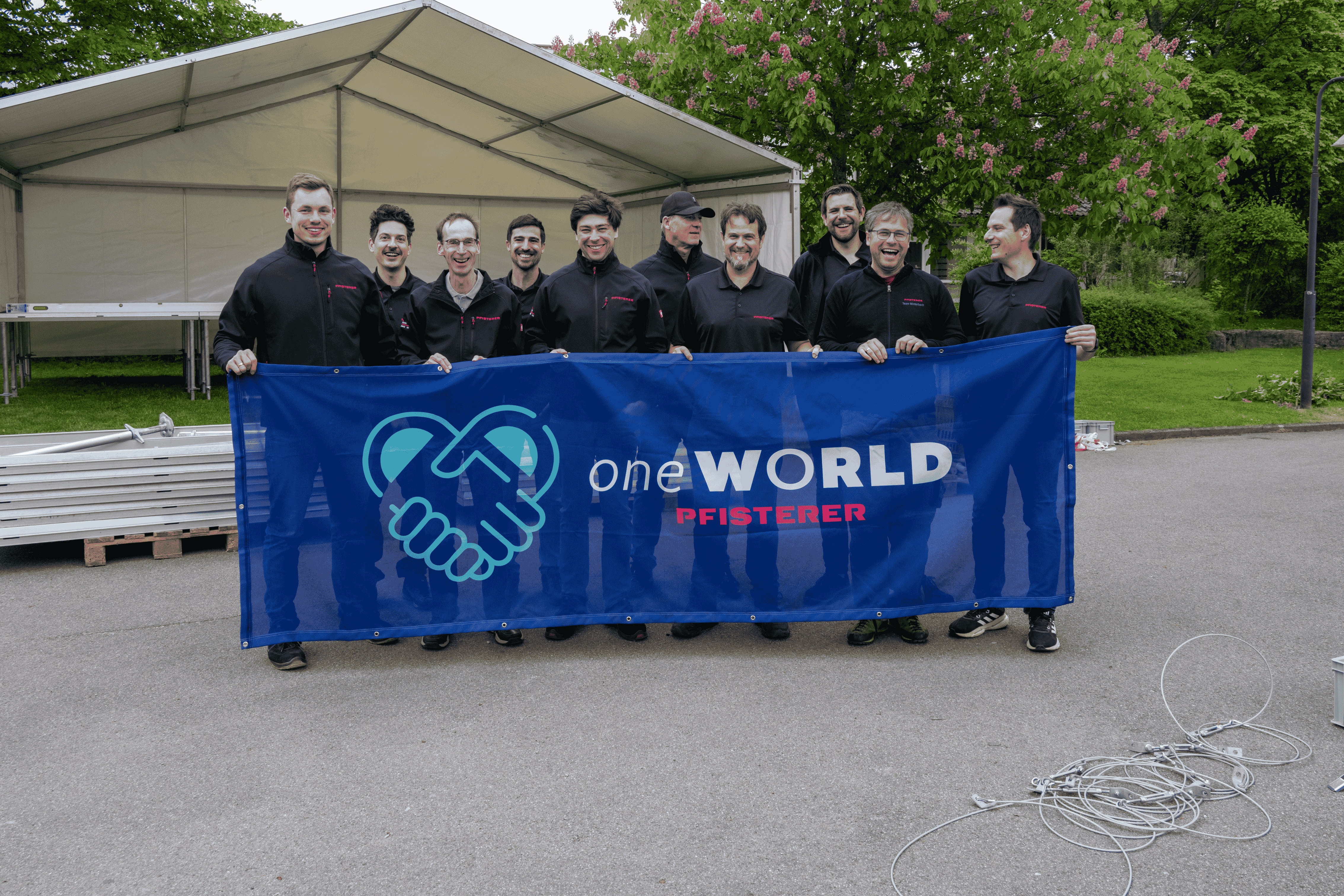 Eine Gruppe von PFISTERER Mitarbeitern, die den one WORLD Banner heben