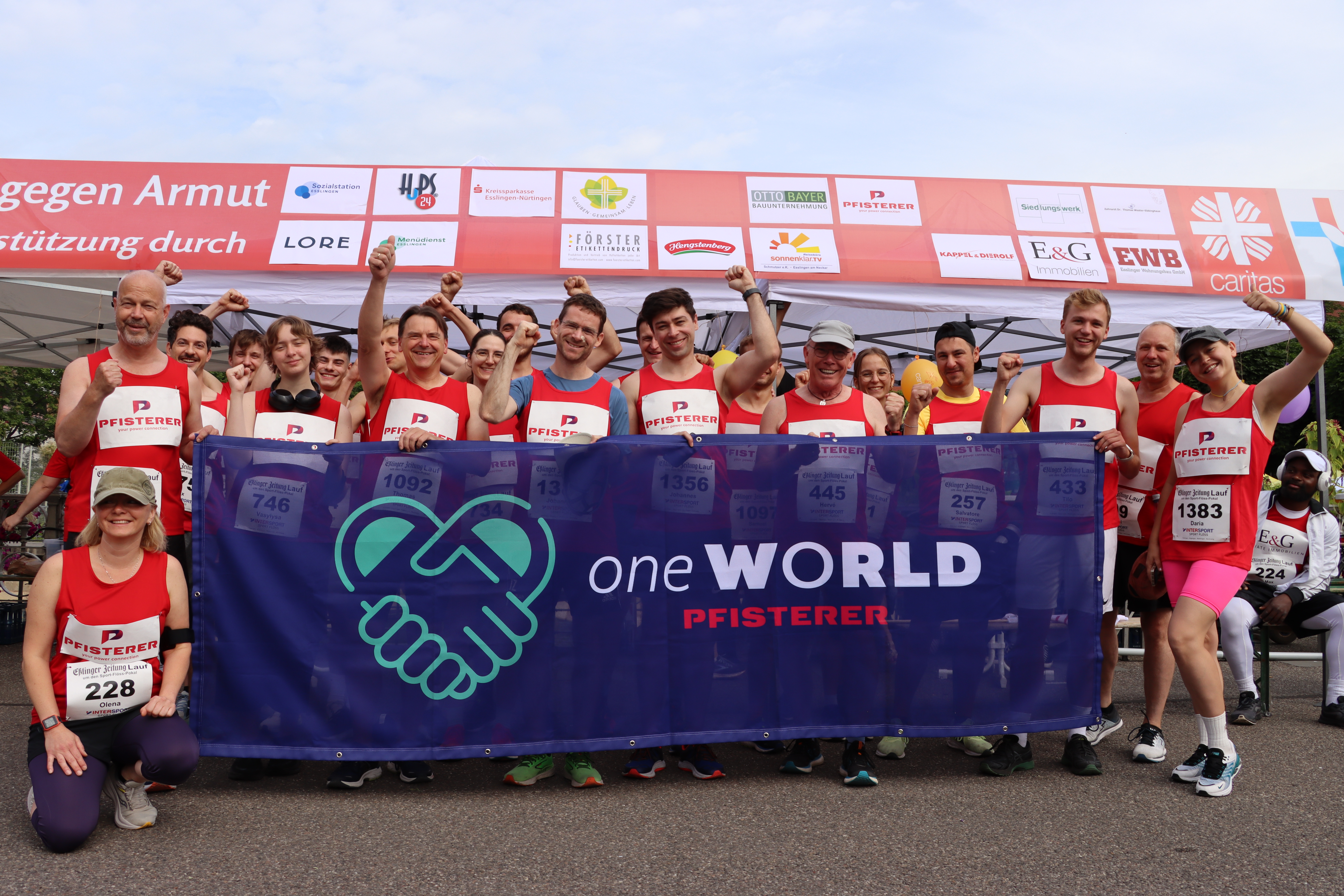 Eine Gruppe Mitarbeiter vor dem PFISTERER oneWorld Banner in Laufklamotten