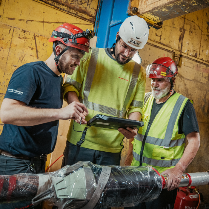 Three PFISTERER Employees watching a tablet