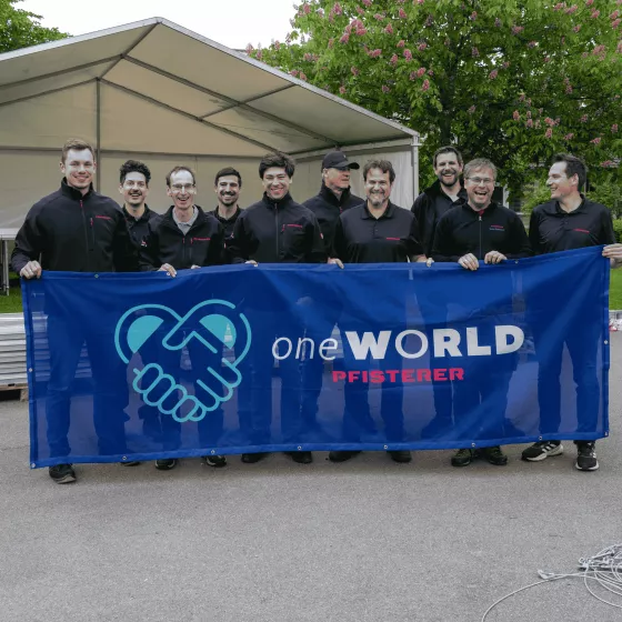 Eine Gruppe von PFISTERER Mitarbeitern, die den one WORLD Banner heben