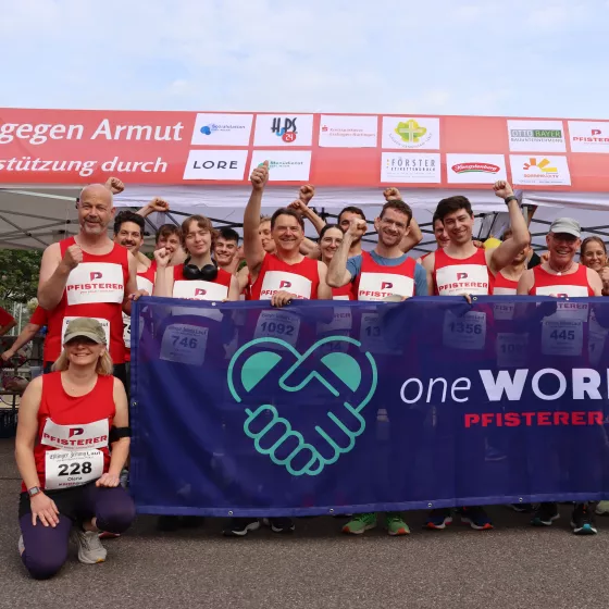 Eine Gruppe Mitarbeiter vor dem PFISTERER oneWorld Banner in Laufklamotten
